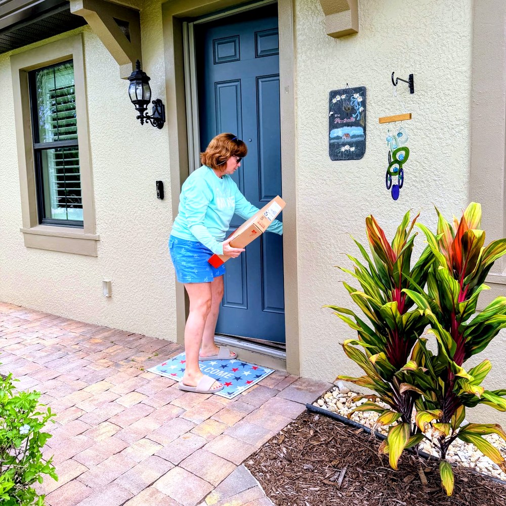 Home Watch Reporter collecting a package at the front door of an Ave Maria home