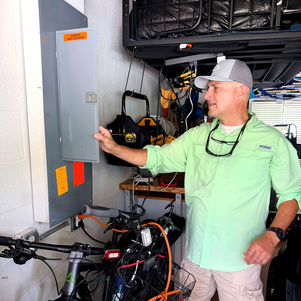 Home Watch Reporter checking an electrical panel in a home garage